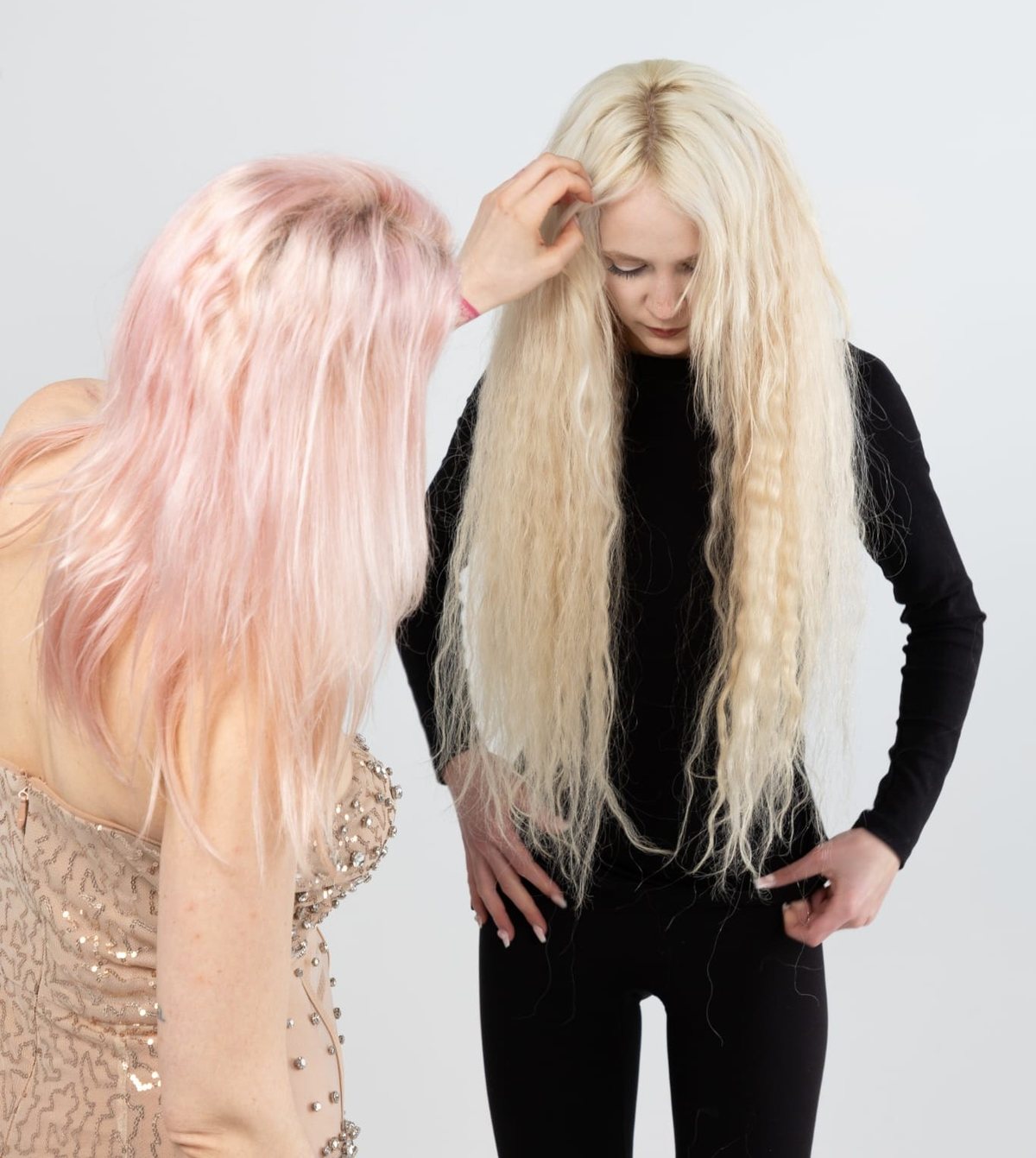 Paula mit rosa Haar neben einem Model mit langem blondem Haar, beide vor weißem Hintergrund