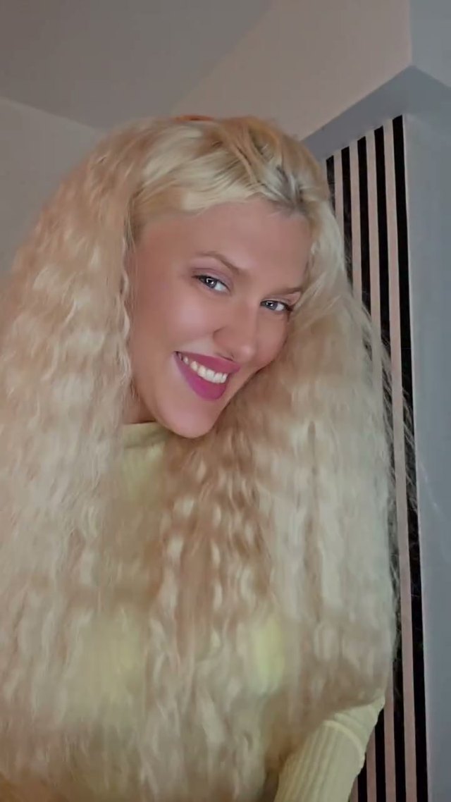 Paula lächelt in die Kamera, langes blondes Haar über der Schulter