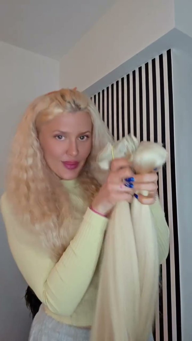Paula hält eine einzelne lange blonde Strähne im Arm