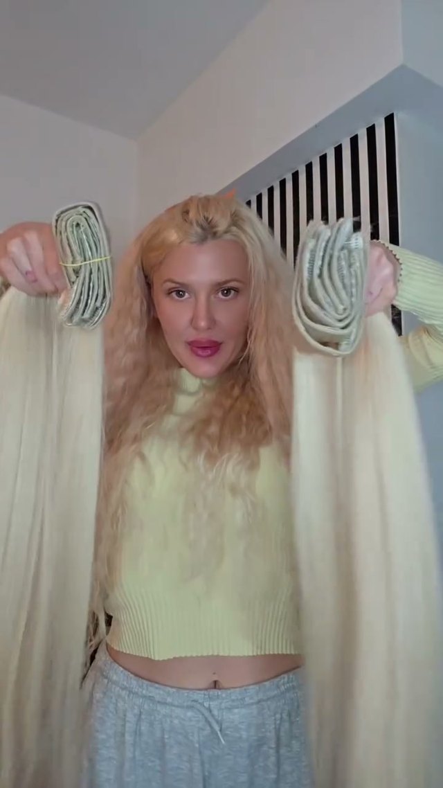 Paula hält in jeder Hand eine sehr lange blonde Tresse hoch
