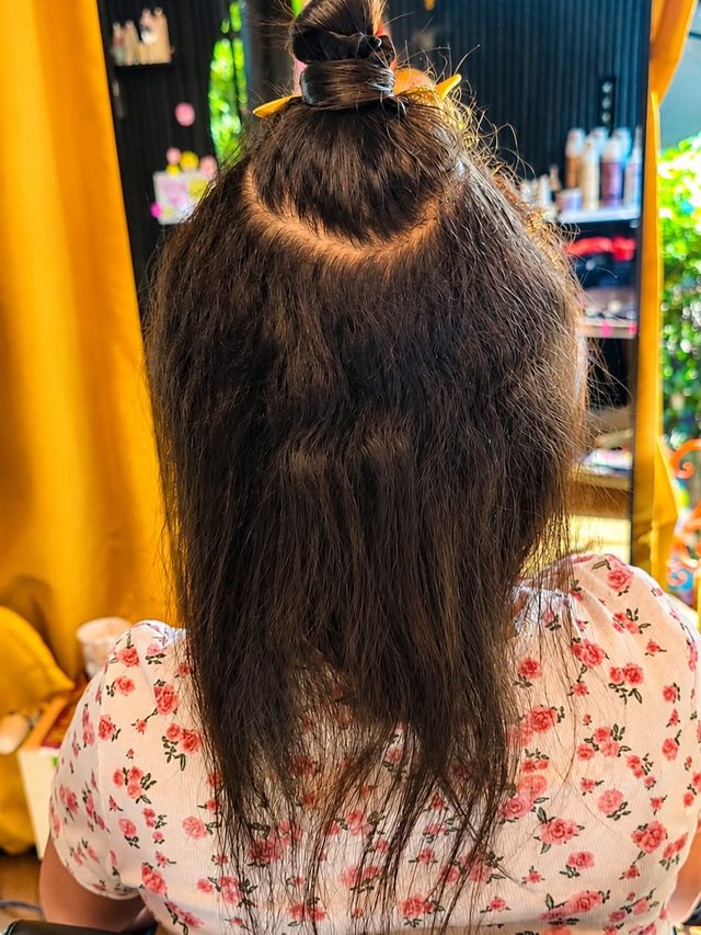 Vorher: dunkelbraunes Haar, oben zu einem Dutt gesteckt