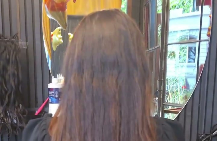Lange braune Haare von hinten, daneben ein ovaler Spiegel
